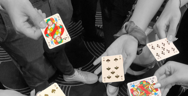 Verschiedene Hände halten je eine Spielkarte