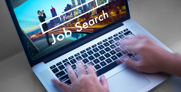Hände die auf der Tastatur eines Laptops tippen, auf dem Bildschirm ist eine Jobsuchmaschine geöffnet